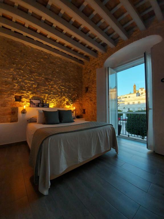 sypialnia z łóżkiem i ceglaną ścianą w obiekcie Alojamientos Plaza de España w mieście Medina Sidonia