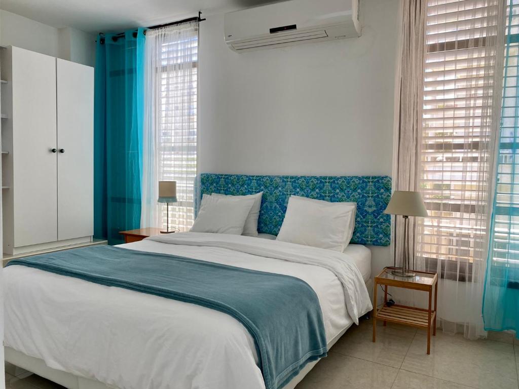 une chambre avec un grand lit et une tête de lit bleue dans l'établissement Sea You Soon!, à Netanya