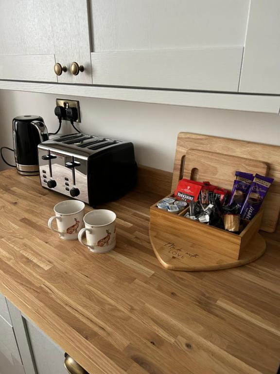 a counter with two coffee cups and a toaster on it at Rosy Bay Cottage in Scarborough