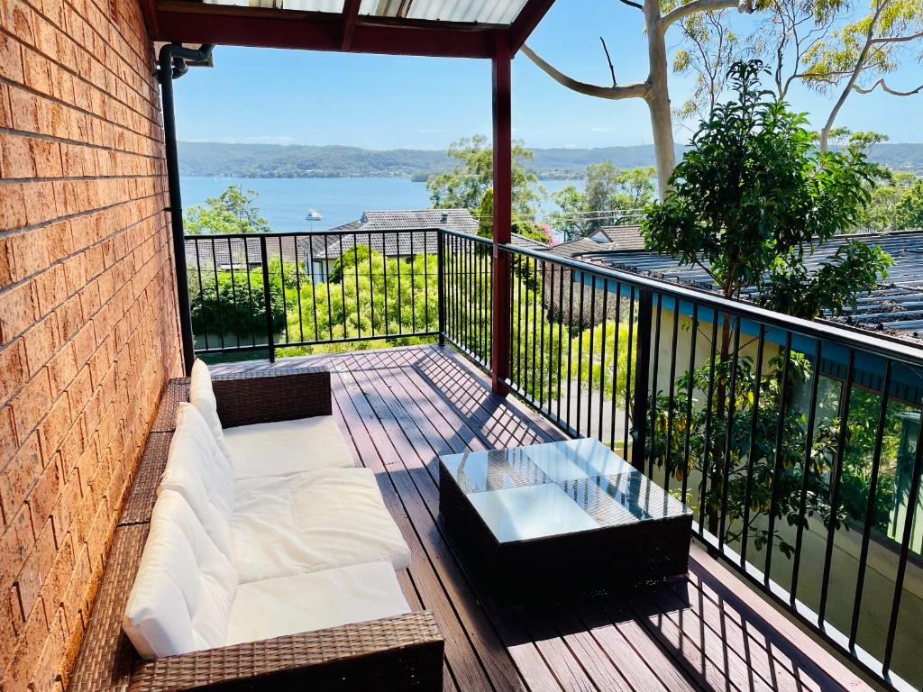 a balcony with a couch and a table on it at 3BR Retreat with Sunset Views over Brisbane Water in Green Point