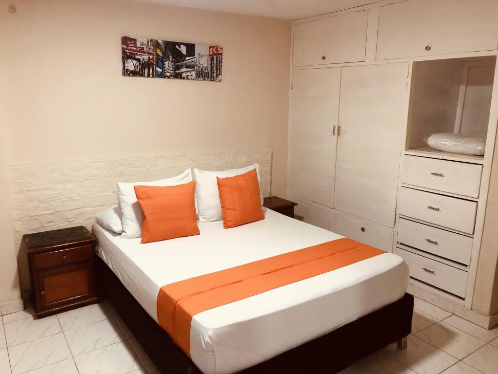 a bedroom with a large bed with orange pillows at Hotel Boston Superior in Barranquilla