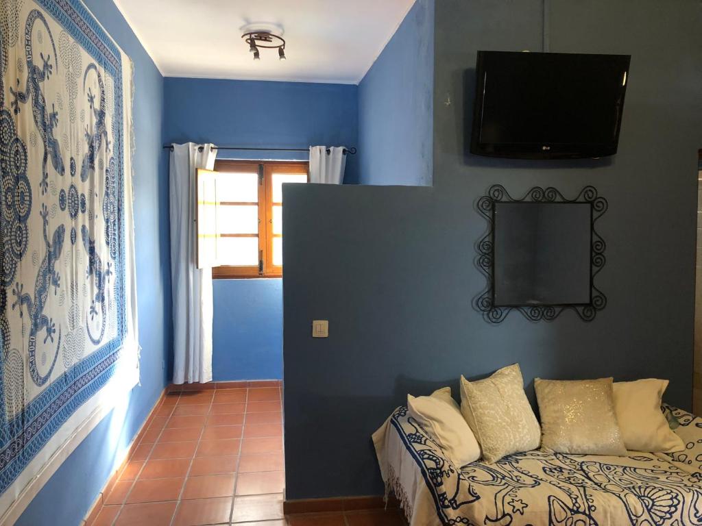 Habitación azul con sofá y TV en la pared en Casona La Orilla 1908 Tías, en Tías