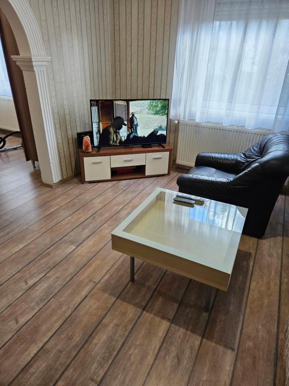 a living room with a tv and a couch and a table at Fenyves Apartman in Tiszafüred