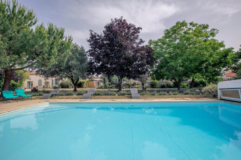 una gran piscina azul con árboles en el fondo en Gîte tout confort (SPA, Sauna, piscine chauffée), en Saint-Vivien