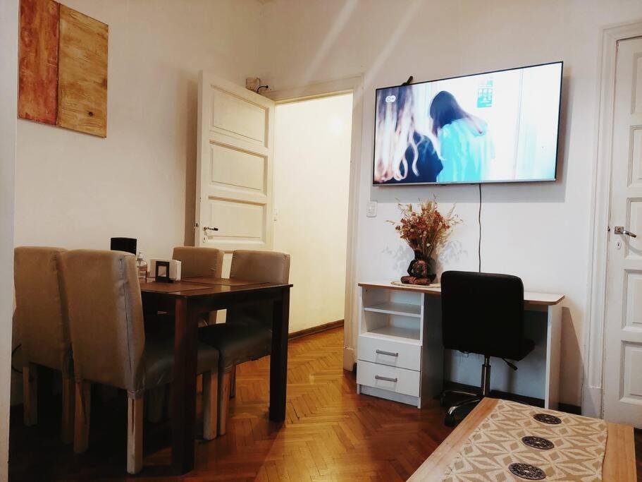 mesa de comedor con sillas y TV de pantalla plana en Lindo Apartamento a una cuadra del obelisco en Buenos Aires