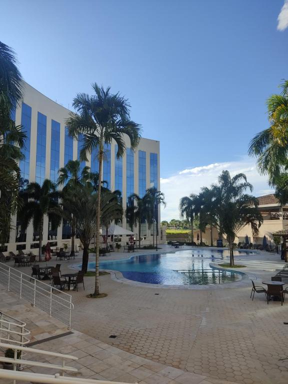 um resort com piscina, palmeiras e um edifício em Condomínio Barretos Thermas Park em Barretos