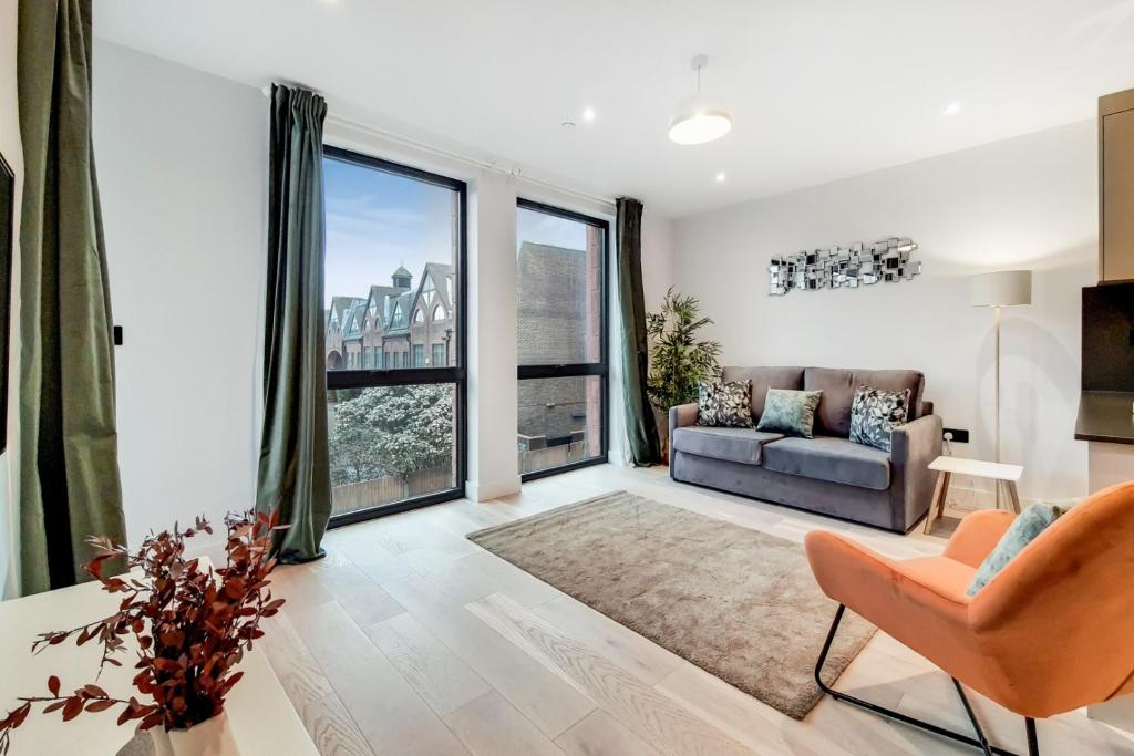 a living room with a couch and a large window at Deluxe Harrow Wembley Apartment in Harrow