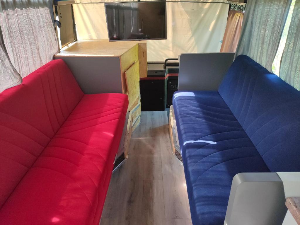dos asientos rojos y azules en una caravana en terrebioBus, en Visnadello