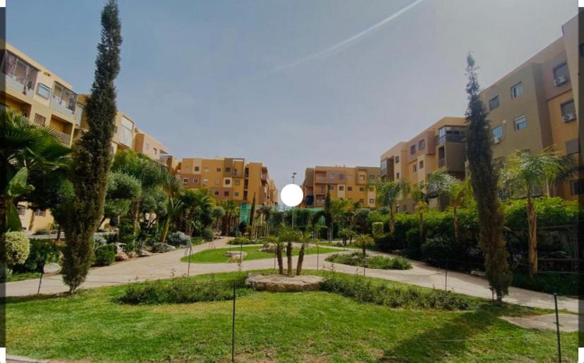 een park in een stad met palmbomen en gebouwen bij Résidence noor marrakech in Marrakesh