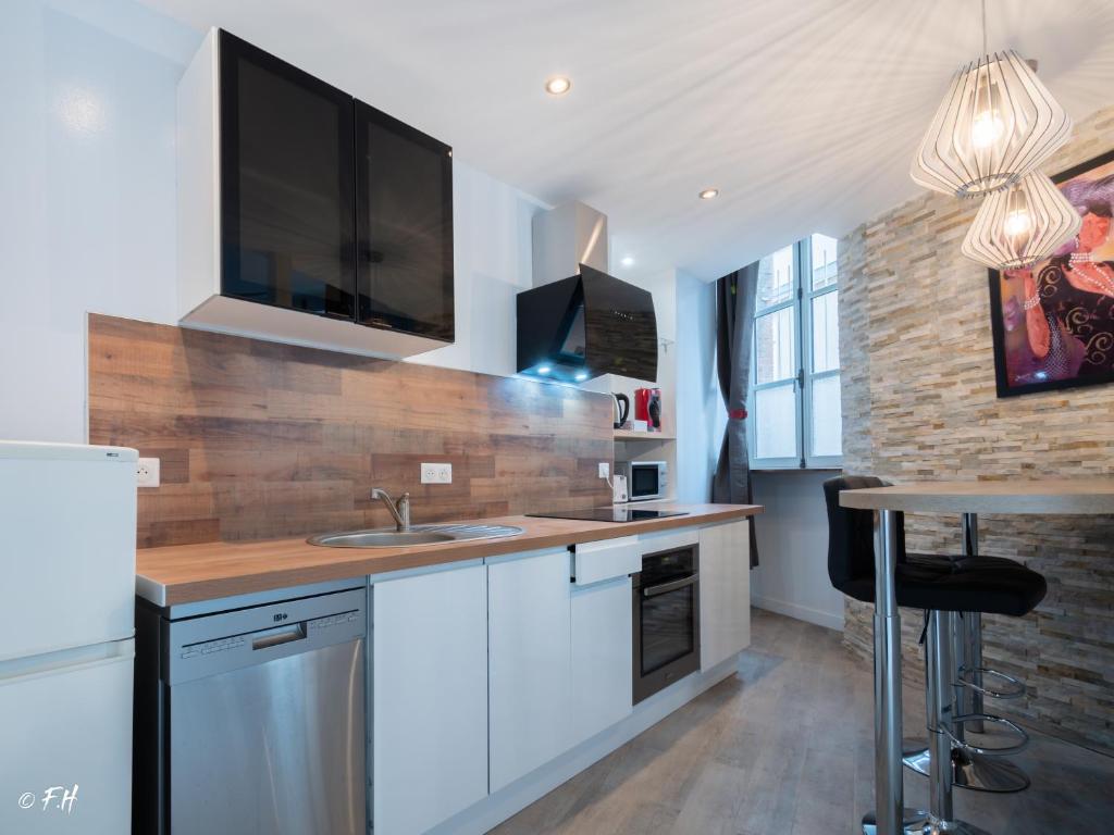 a kitchen with white cabinets and a tv on the wall at LE VIEUX LAVAL in Laval