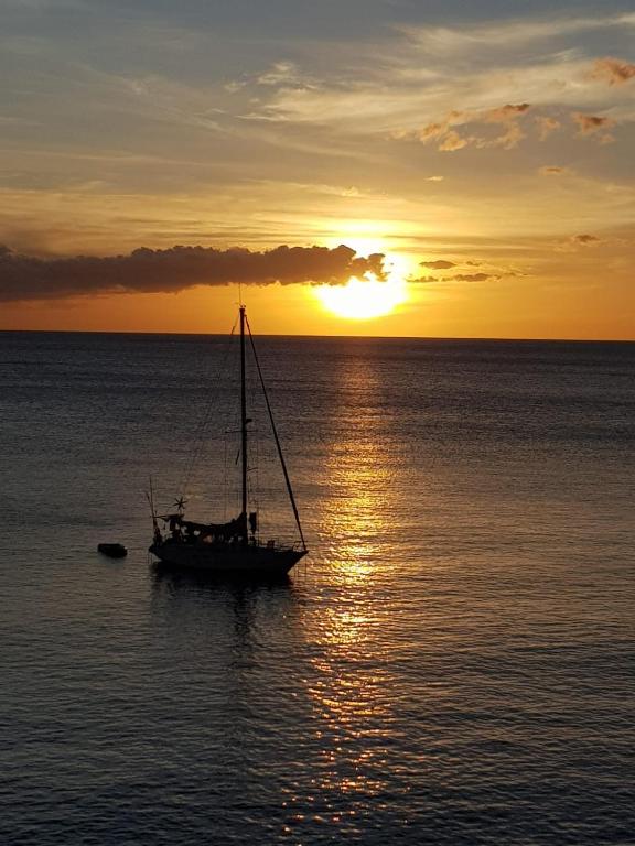 a boat in the ocean with the sunset in the background at Superbe appartement vue mer - résidence de standing in Schœlcher