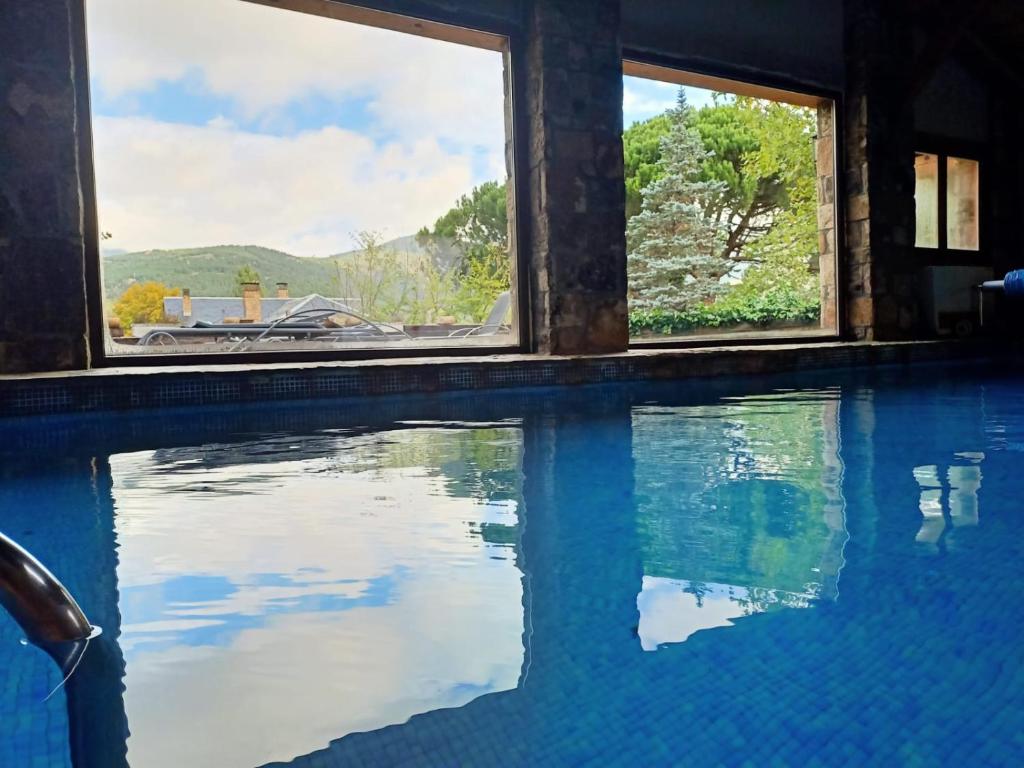 una piscina con vistas a las montañas a través de las ventanas en Casa Bonita Navacerrada, en Navacerrada