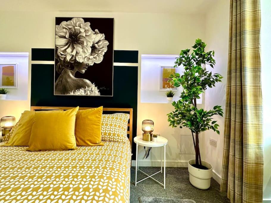 a bedroom with a bed with yellow pillows and a plant at Massive New 8 bedroom House Sleeps up to 21 - Accepts Groups - Great Location - FREE Parking - Fast WiFi - Smart TVs - sleeps up to 21 people - Close to Bournemouth & Poole Town Centre & Sandbanks in Bournemouth