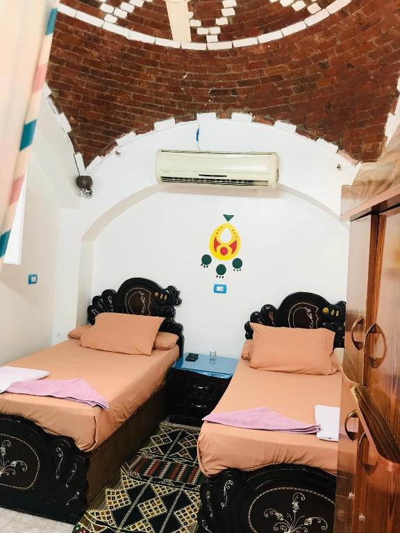 two beds in a room with a ceiling at Gamal Robob Nubian Guest House in Aswan