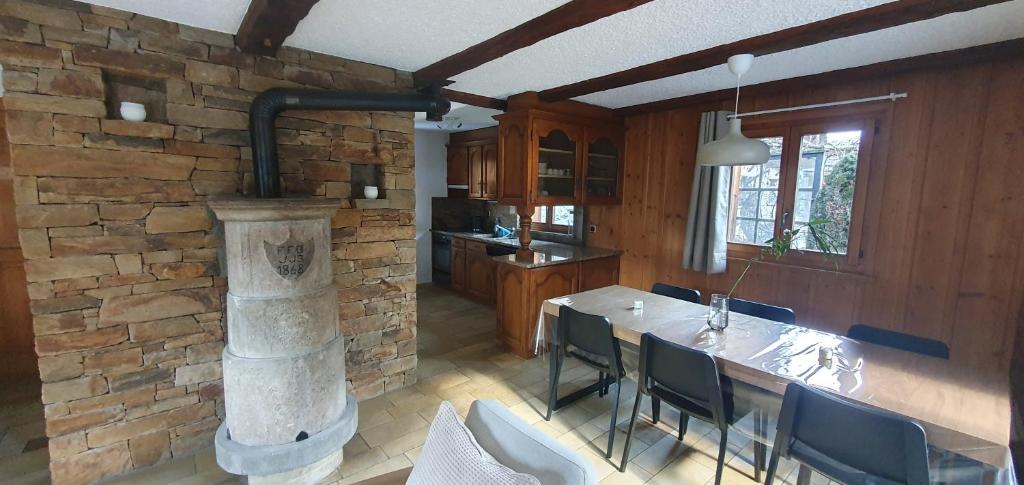 a kitchen and dining room with a stone fireplace at Chalet, Bagnes, Suisse in Le Châble