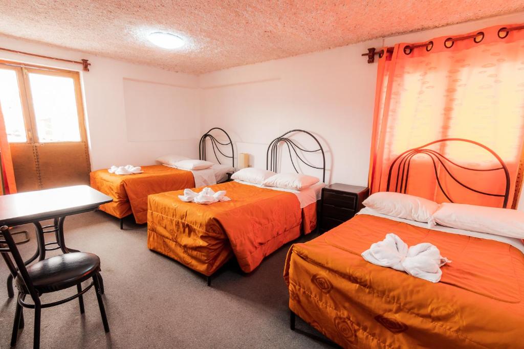 Zimmer mit 3 Betten und einem Tisch in der Unterkunft Hotel San Francisco de Paula Ayacucho in Ayacucho