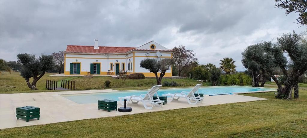 a villa with a swimming pool in front of a house at Monte das Hortas Velhas in Viana do Alentejo