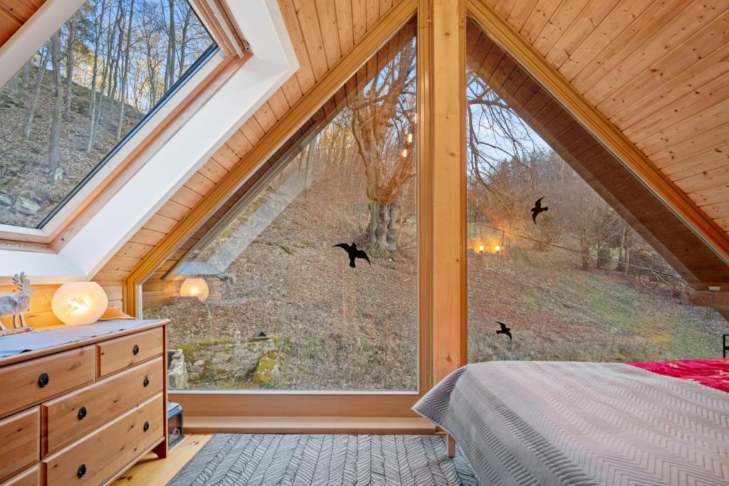 a bedroom with a large window with birds flying outside at Srub Pod Lípou - Skryje 