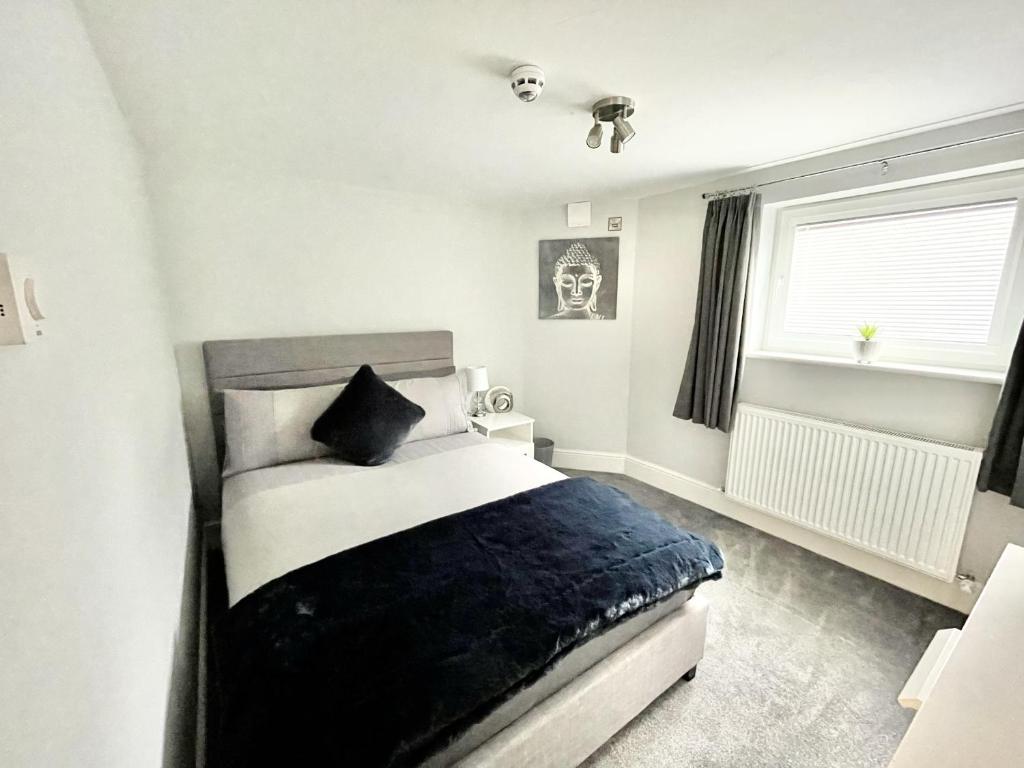 Schlafzimmer mit einem schwarzen und weißen Bett und einem Fenster in der Unterkunft LYMM LIVING in Warrington