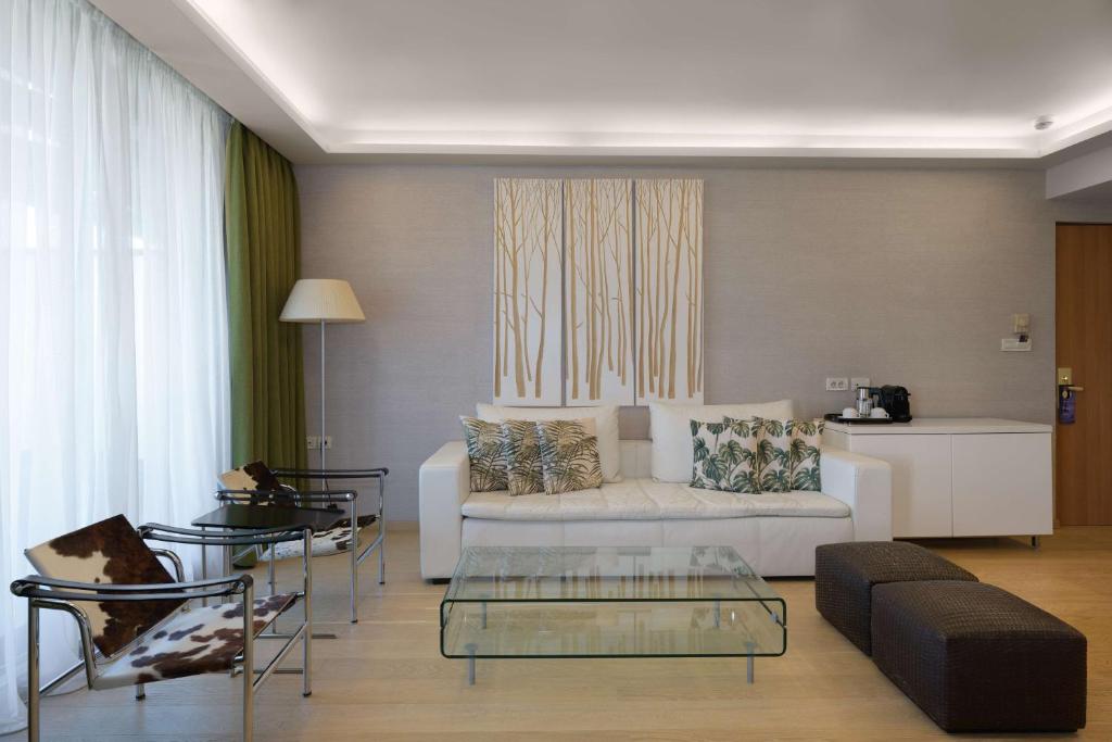 a living room with a white couch and chairs at Radisson Blu Park Hotel Athens in Athens