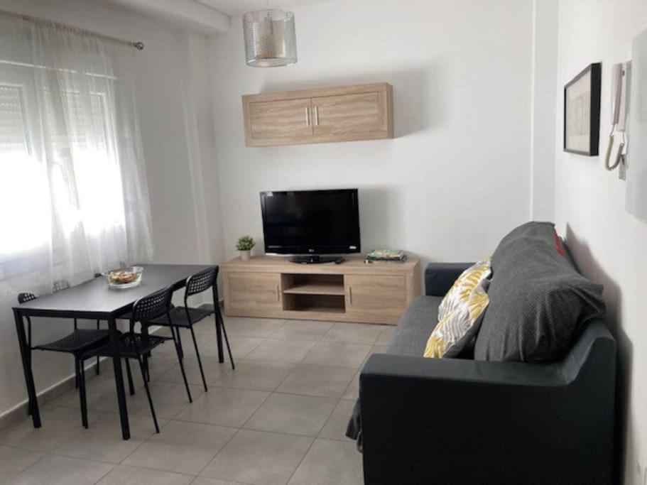 sala de estar con sofá, mesa y TV en Fantástico apartamento en Triana en Sevilla