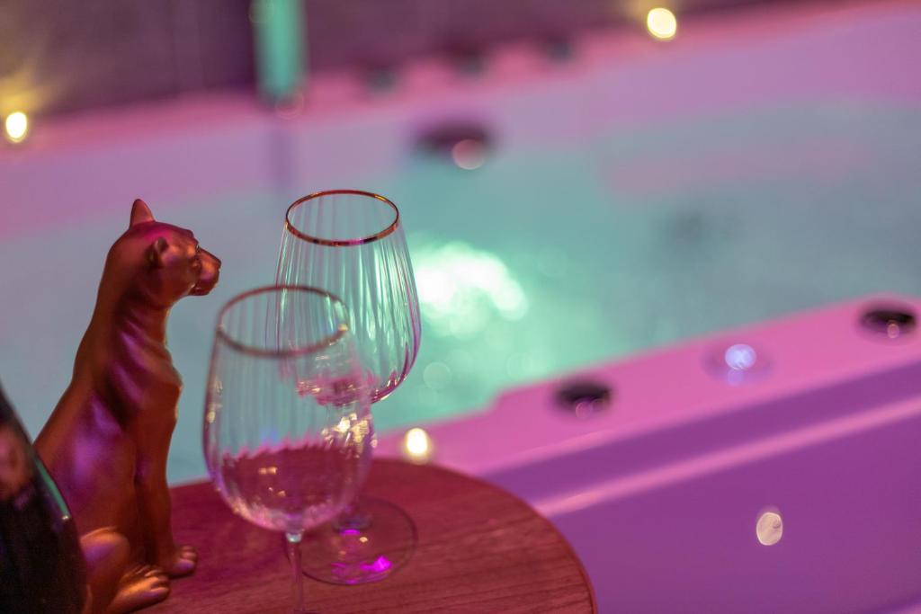 two wine glasses sitting on top of a wooden table at Suite Amazonia ~ Balnéo ~ Arrivée Autonome in Rouen