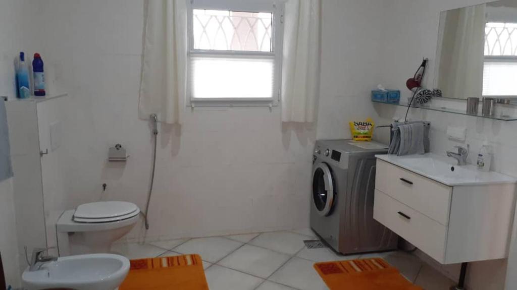 a bathroom with a toilet and a washing machine at Babhilds Residence in Bakau