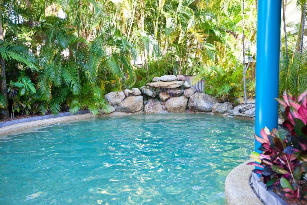 a swimming pool in a tropical garden with trees at Trinity Beach Pacific in Trinity Beach