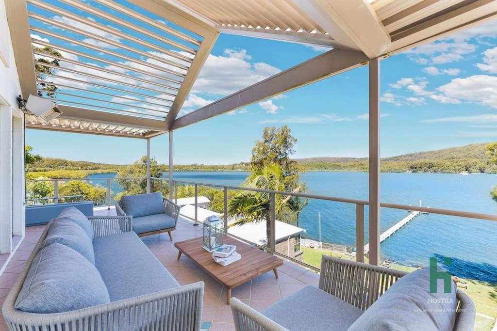 雪梨的住宿－Central Coast Moon Lake Resort，带沙发并享有水景的天井。