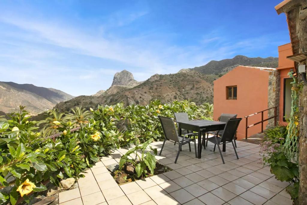 a patio with a table and chairs and mountains at Casa Rural La Presa in Vallehermoso