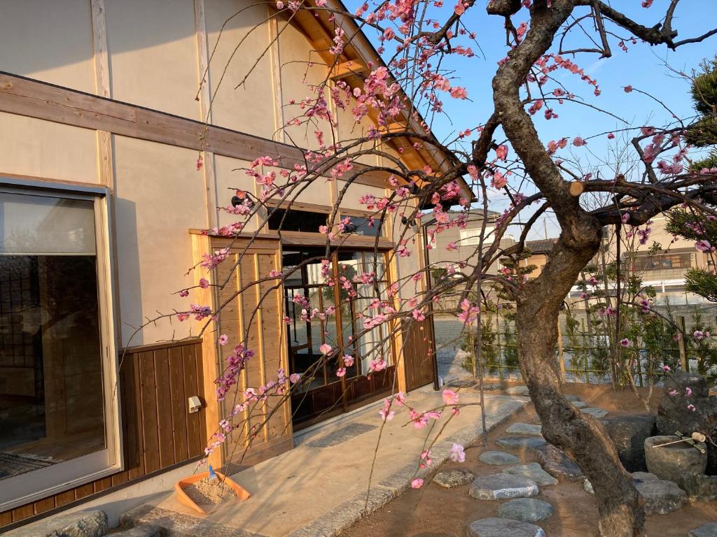 einen Baum mit rosa Blumen vor einem Gebäude in der Unterkunft 小舞庵 Komaian in Tokushima