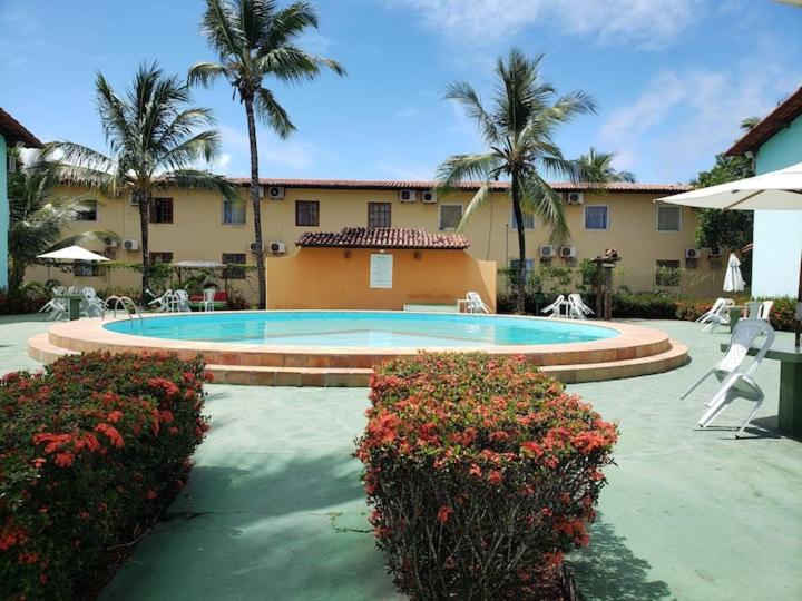 a swimming pool in front of a building with palm trees at Pé na Areia in Porto Seguro