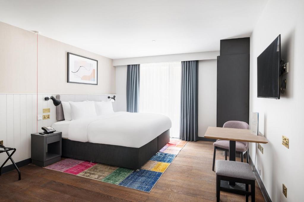 ブライトン＆ホーブにあるStaybridge Suites Brighton, an IHG Hotelのベッドとテーブルが備わるホテルルームです。