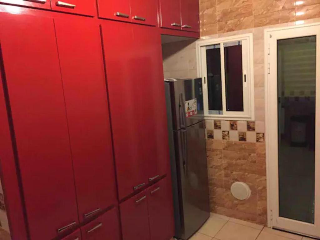 a kitchen with red cabinets and a refrigerator at Nouveau Appartement Avec Un Parking Gratuit in La Marsa