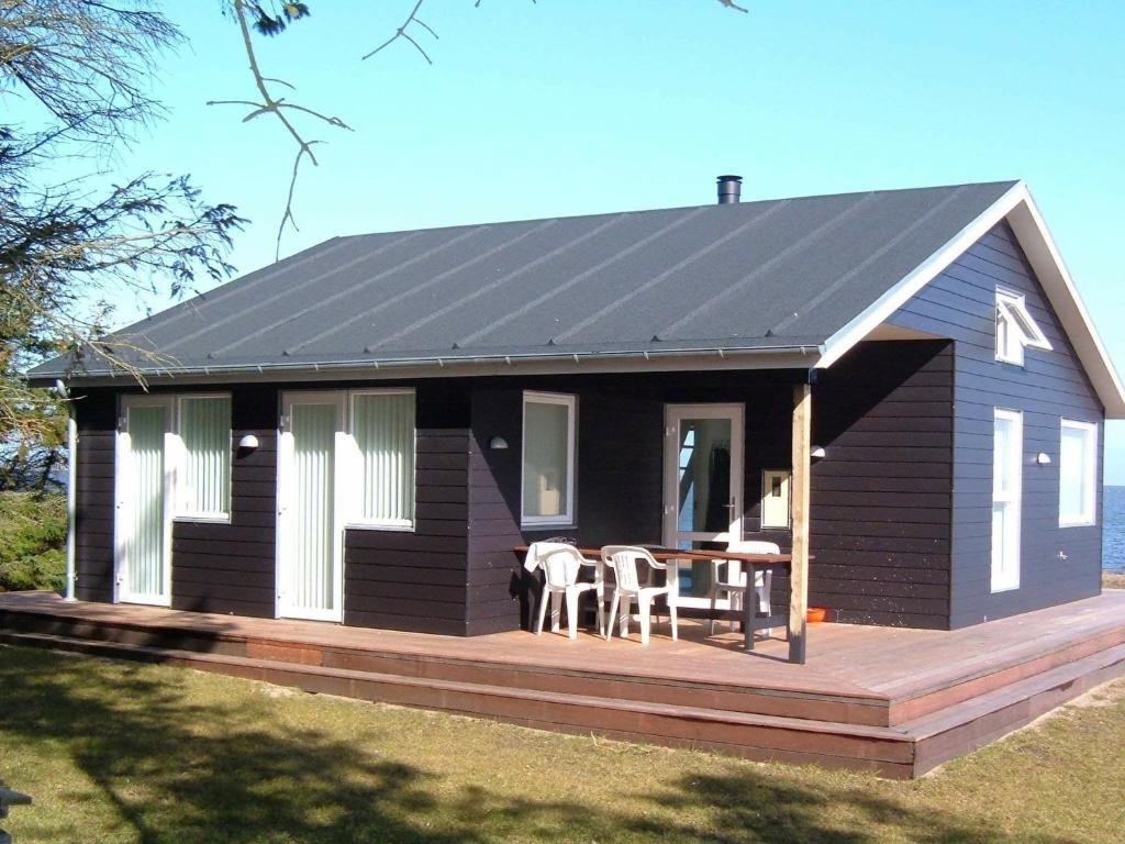 ein schwarzes Haus mit einem Tisch auf einer Terrasse in der Unterkunft Two-Bedroom Holiday home in Harboøre 4 in Harboør