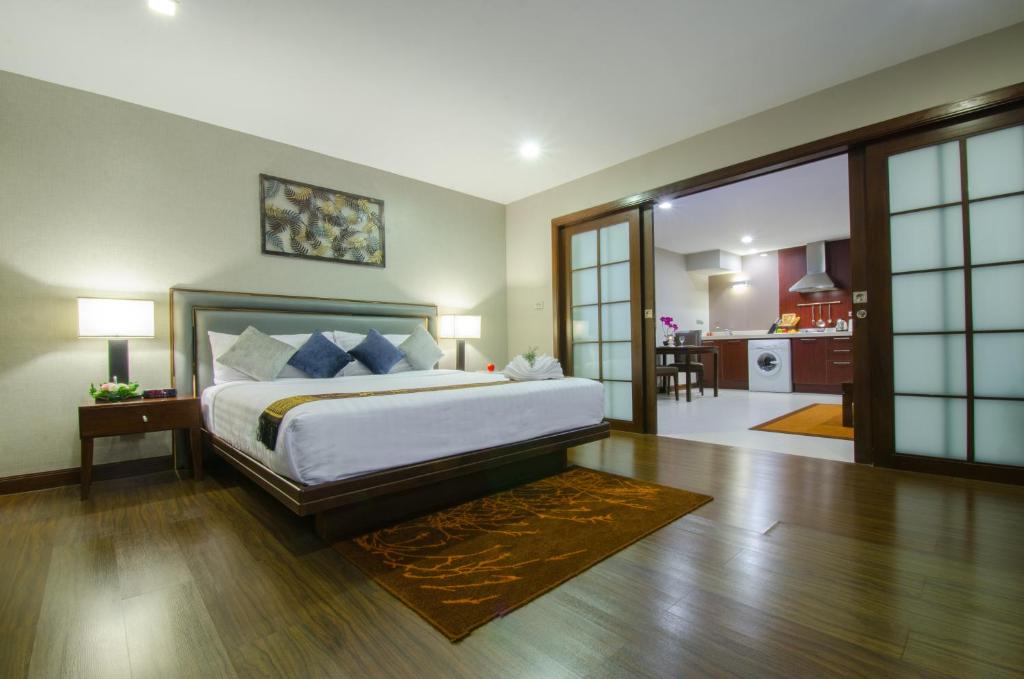 Grand Asoke Suites Boutique Residence في بانكوك: غرفة نوم مع سرير وغرفة معيشة