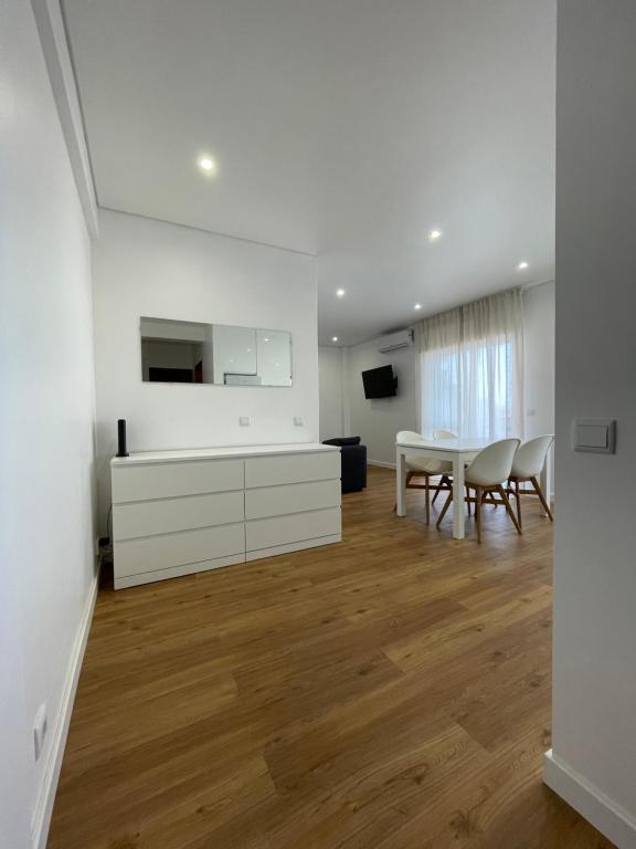 a white living room with a table and chairs at Monte Gordo South Pearl Apartment in Monte Gordo