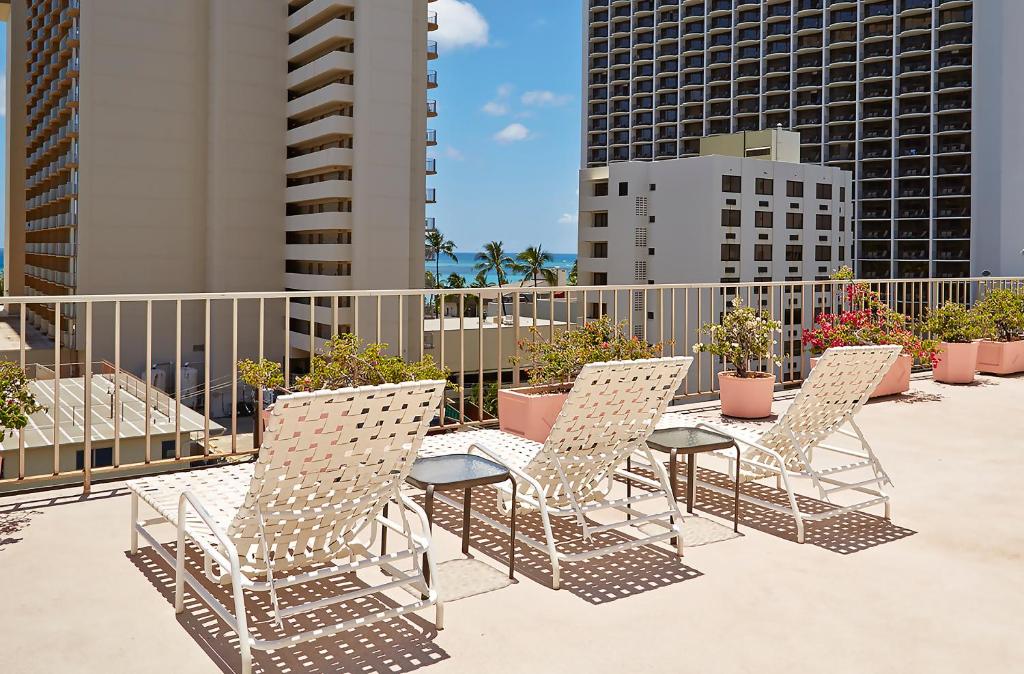 een rij stoelen en tafels op een balkon bij Ewa Hotel Waikiki in Honolulu