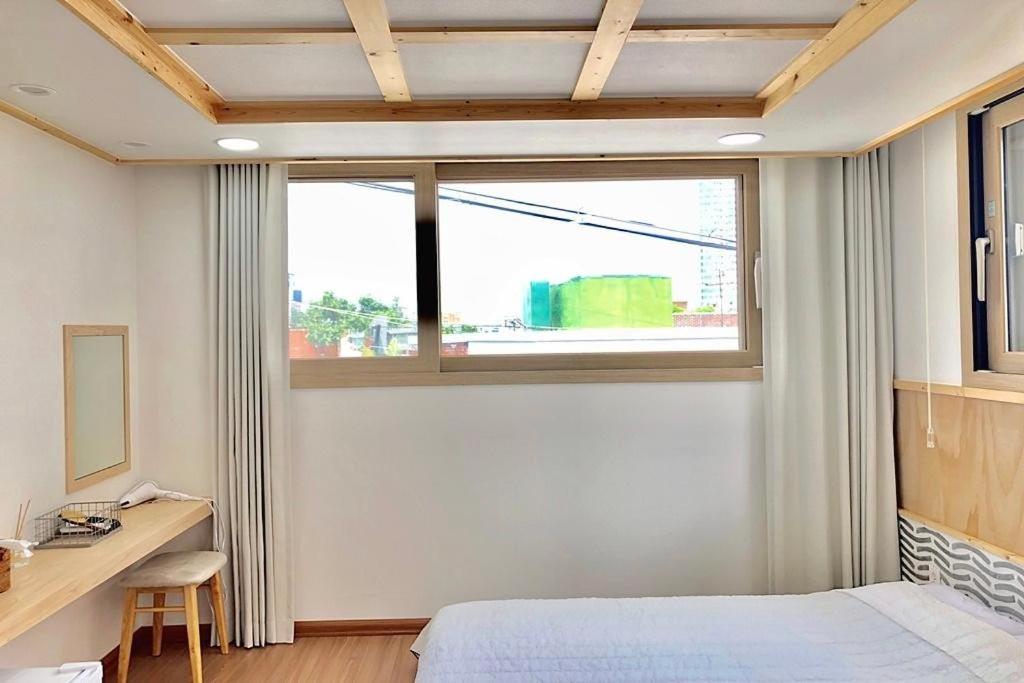 um quarto com uma cama, uma secretária e uma janela em Cheukhu-dong 19street Guesthouse em Mokpo