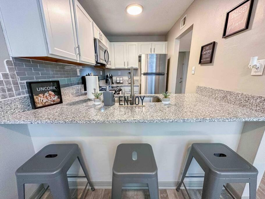 two pictures of a kitchen with two stools at a counter at WOO LOFT- King Bed- Downtown BHM in Birmingham