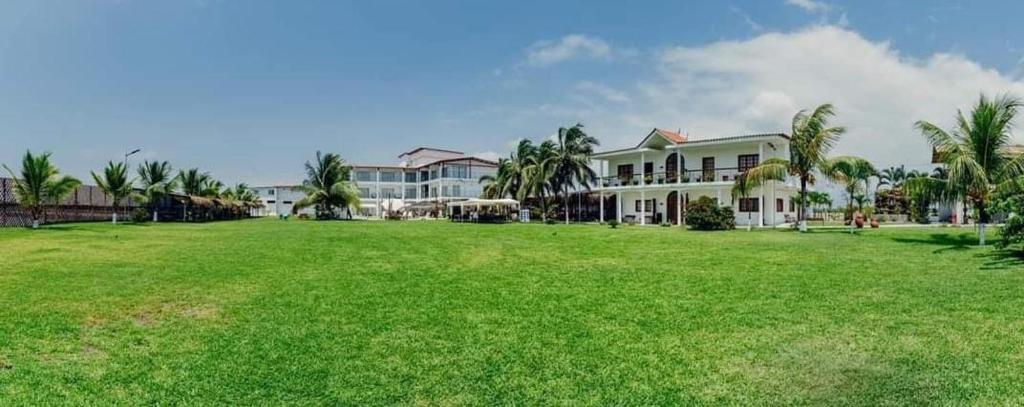 a large grass field in front of a large building at Hotel Hacienda Guamito in Puerto Pizarro