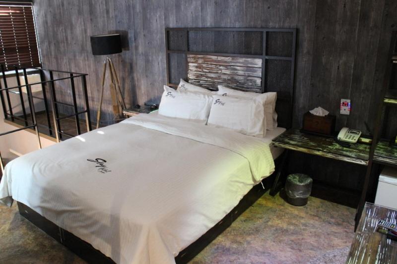 1 dormitorio con 1 cama blanca grande y teléfono en Jeonju Stay Hotel, en Jeonju