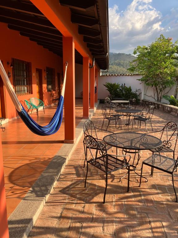 d'une terrasse avec des tables, des chaises et un hamac. dans l'établissement La Casa de Cafe Bed and Breakfast, à Copan Ruinas