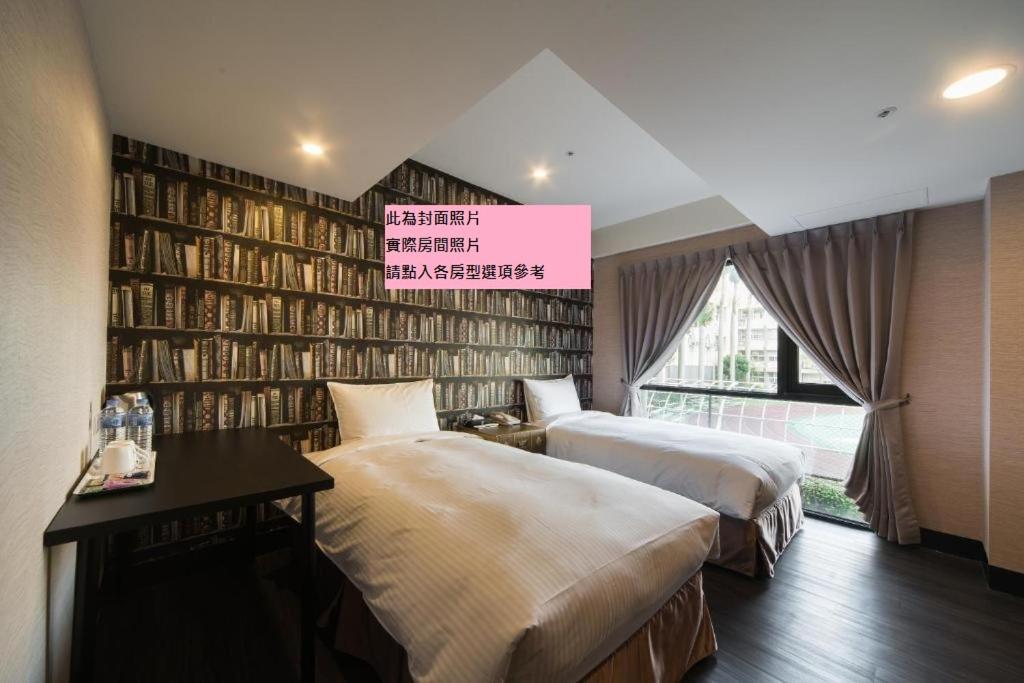 um quarto com duas camas e uma parede de livros em Hotel Fun - Linsen em Taipei