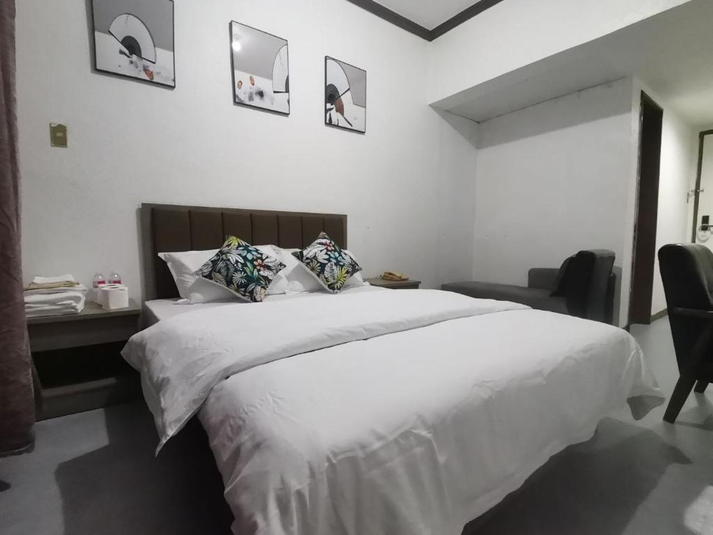 een slaapkamer met een groot wit bed en een stoel bij TemporaryHome -susan in Manilla