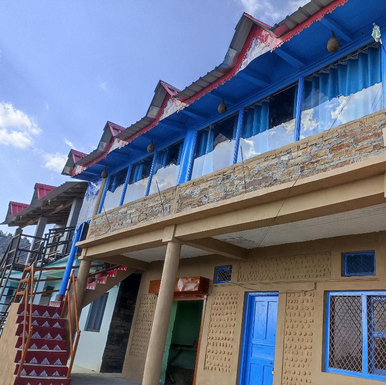 a building with a blue roof and a staircase at Nature Valley Homestay Shaukiyathal in Panuānaula