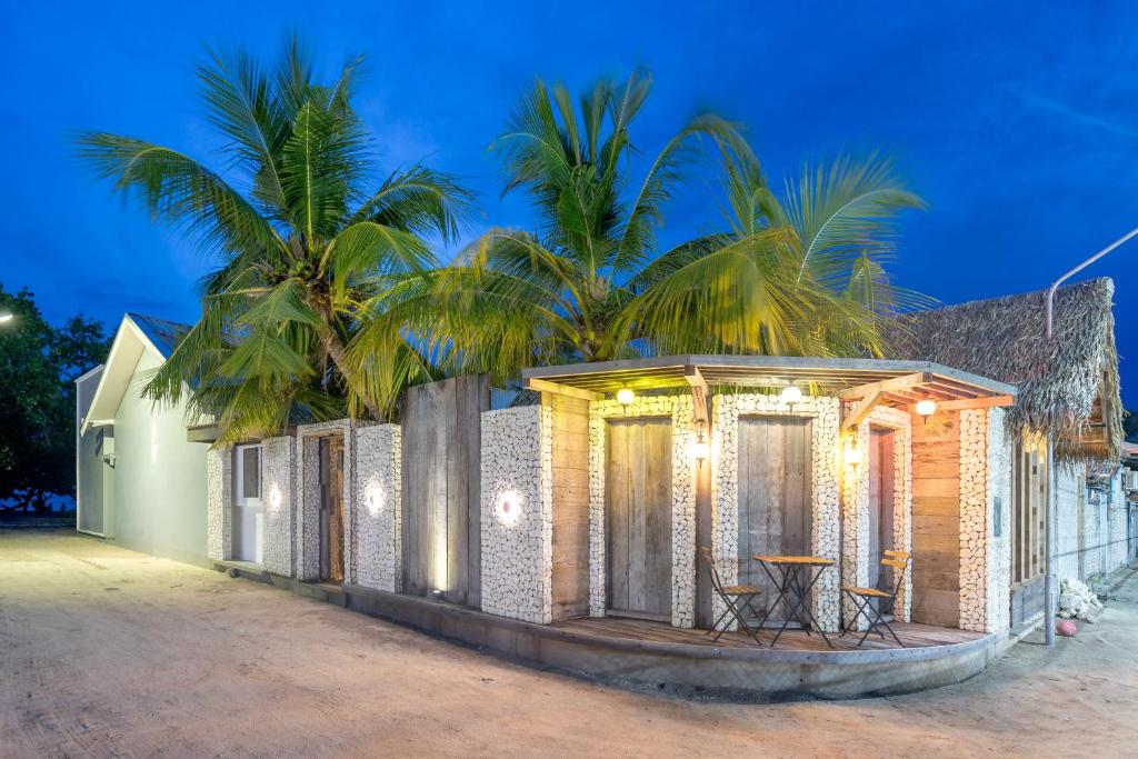 a building with a table and palm trees in the background at Brickwood Veli in Rasdu