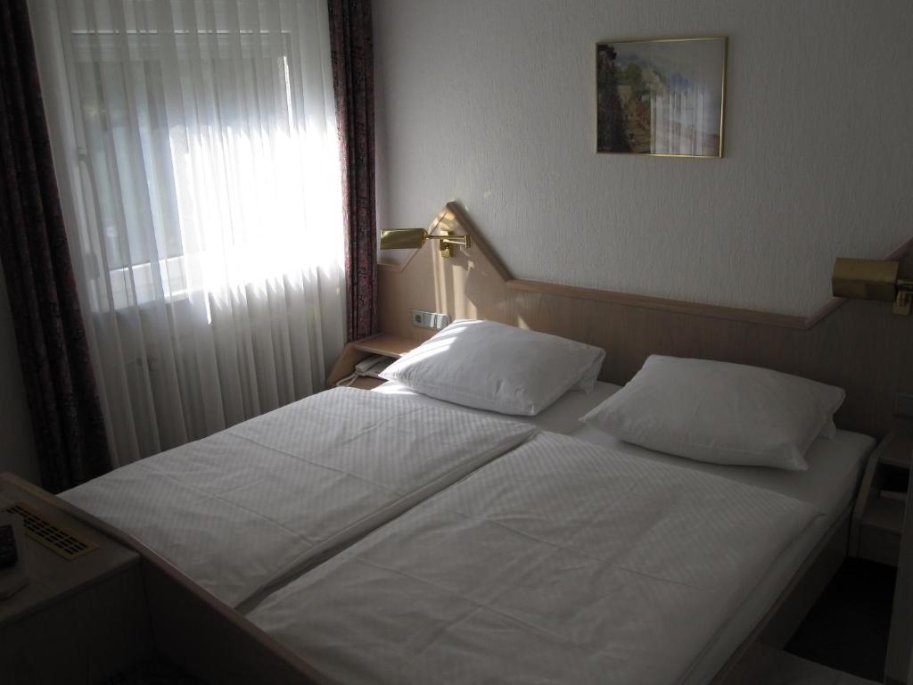 ein Schlafzimmer mit einem Bett mit zwei Kissen und einem Fenster in der Unterkunft Hotel Maifelder Hof in Mayen
