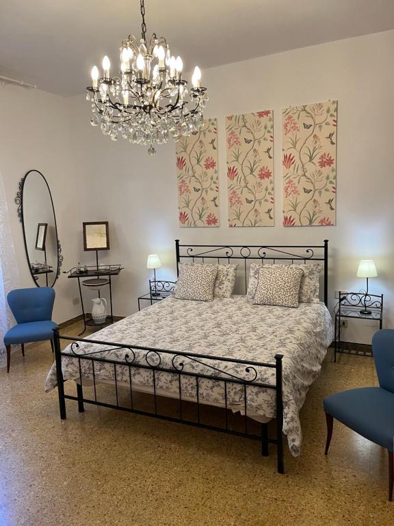 a bedroom with a bed and two chairs and a chandelier at La Corte Apartment in Florence
