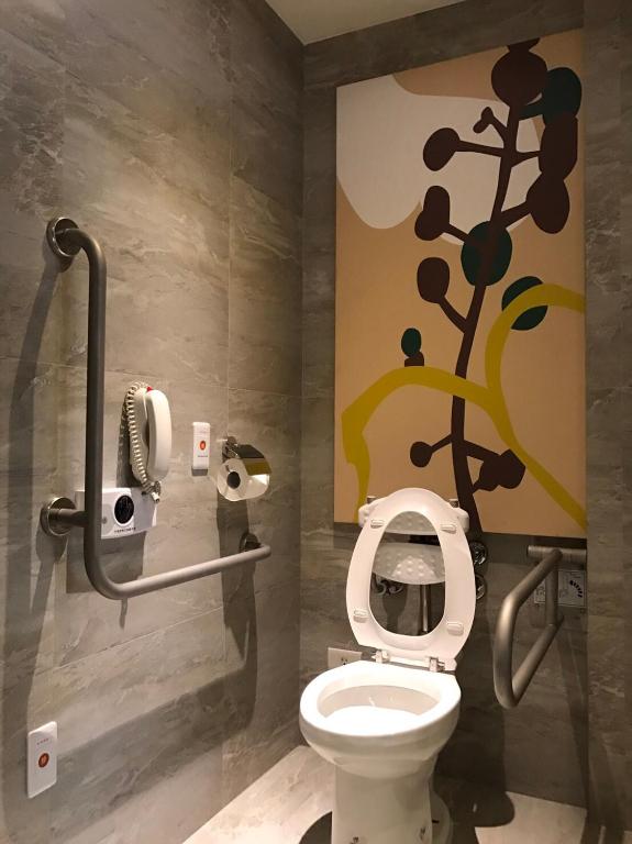 a bathroom with a toilet with a flower painted on the wall at K Hotel Taipei Songjiang in Taipei